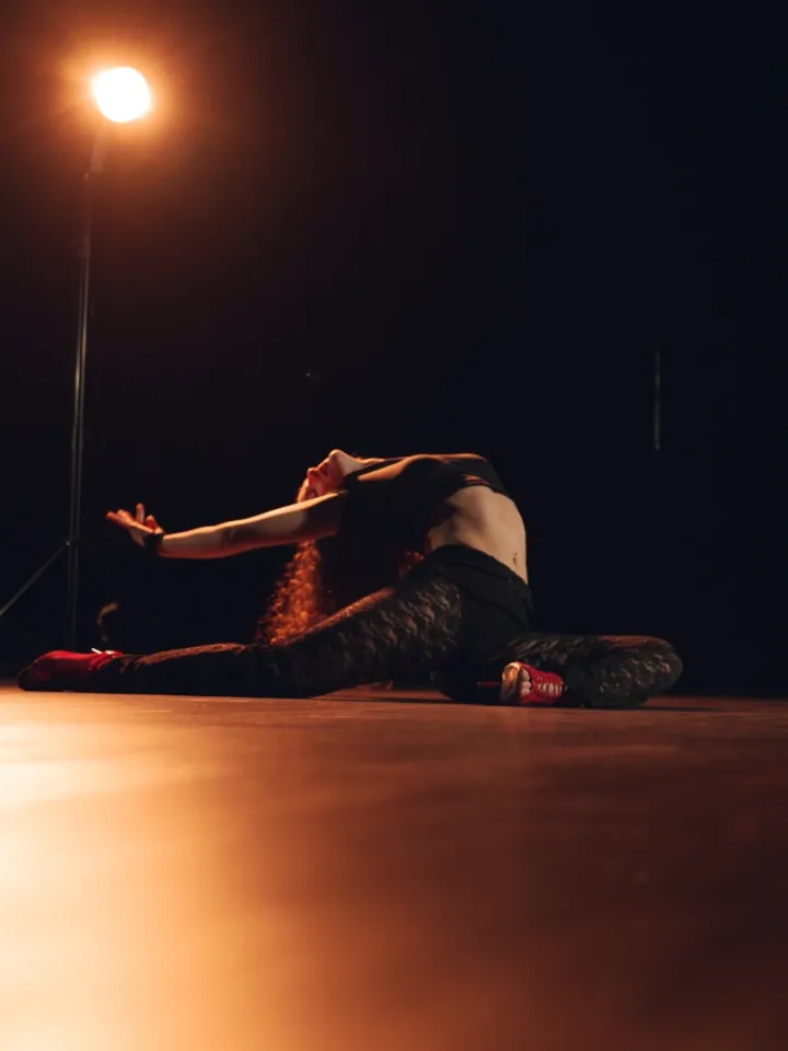 Bailarina de On Heels en el piso del estudio, en tacos, bajo una luz cálida